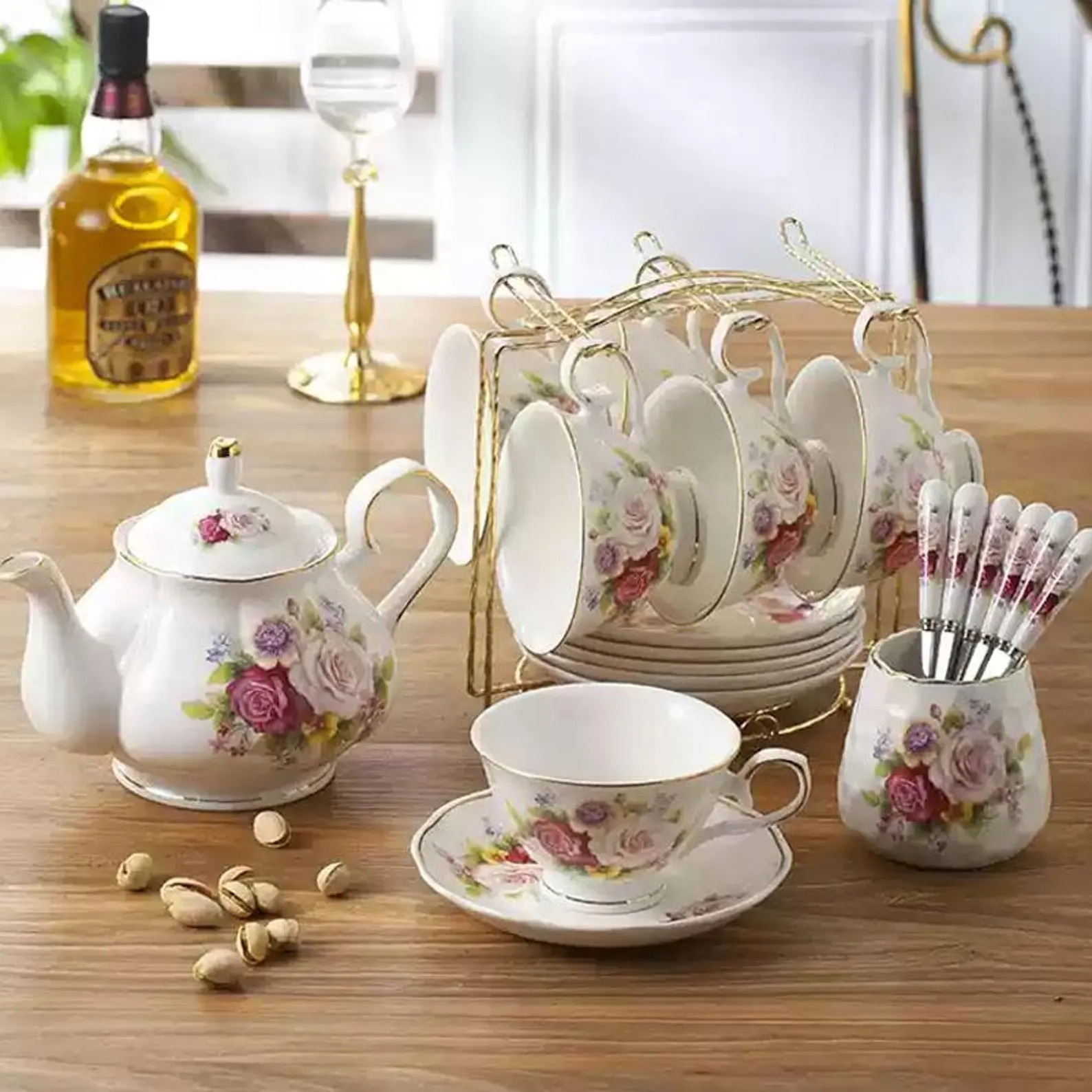 Floral bone china tea set with teapot, cups, saucers and gold rims on a wooden table